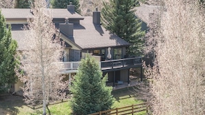 Ein zweigeschossiges Haus mit Balkon, umgeben von Bäumen und einem Holzzaun.