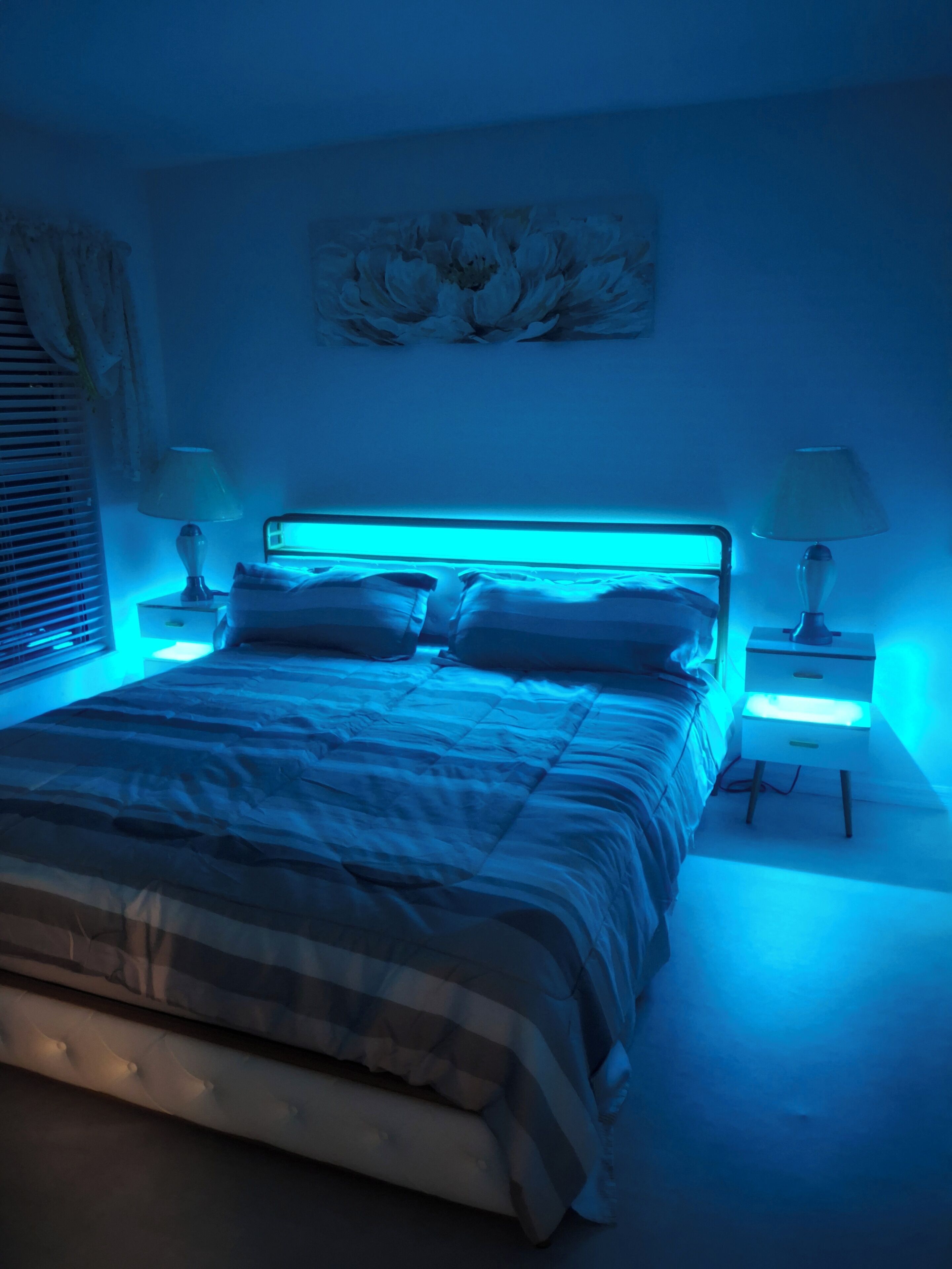 Een slaapkamer met een bed, twee nachtkastjes en een wandlamp.