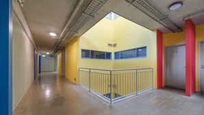 A corridor with a yellow wall, a metal railing, and a door labeled 4.65. - Chic Apartment in Heart of Adelaide (Adelaide)
