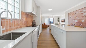 Een moderne keuken met witte kastjes, een roestvrijstalen spoelbak en een raam met uitzicht.