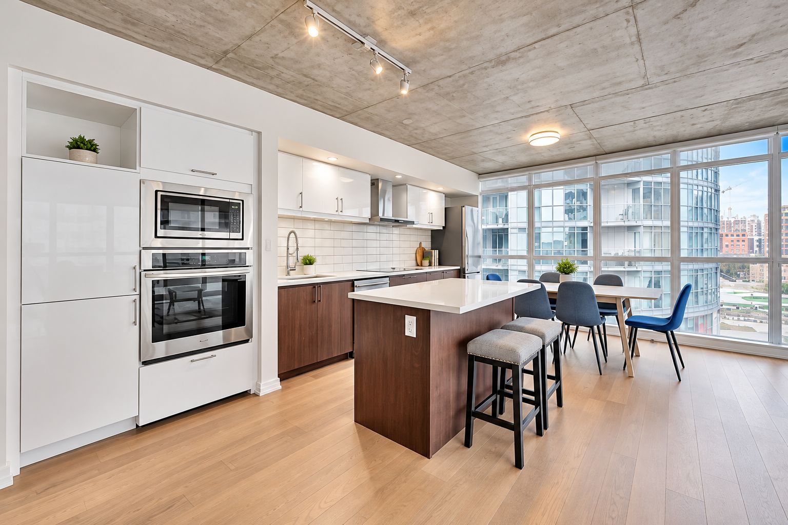 A modern kitchen with built-in appliances, a central island, and a dining area with chairs.
