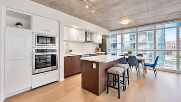 Una cocina moderna con electrodomésticos integrados, una isla central y un comedor con sillas.