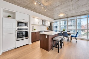Una cocina moderna con electrodomésticos integrados, una isla central y un comedor con sillas.
