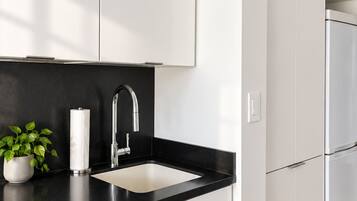 Una cocina moderna con armarios blancos, encimera negra y refrigerador de acero inoxidable.
