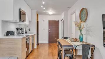 Una cocina moderna con armarios de madera, una mesa de comedor con sillas y un jarrón decorativo en la pared.
