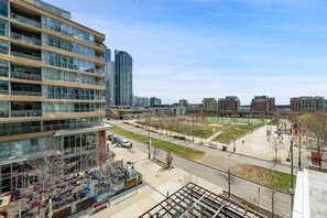 A modern building with multiple floors, large windows, and a parking area with a few cars. - HostlyStays Luxury Suites  (Toronto)