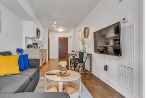 A modern living room with a sofa, coffee table, and dining area. - HostlyStays Luxury Suites  (Toronto)