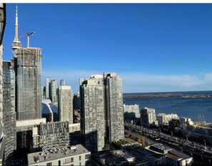 A cityscape with high-rise buildings, a prominent tower, and a waterfront. - HostlyStays Luxury Suites  (Toronto)