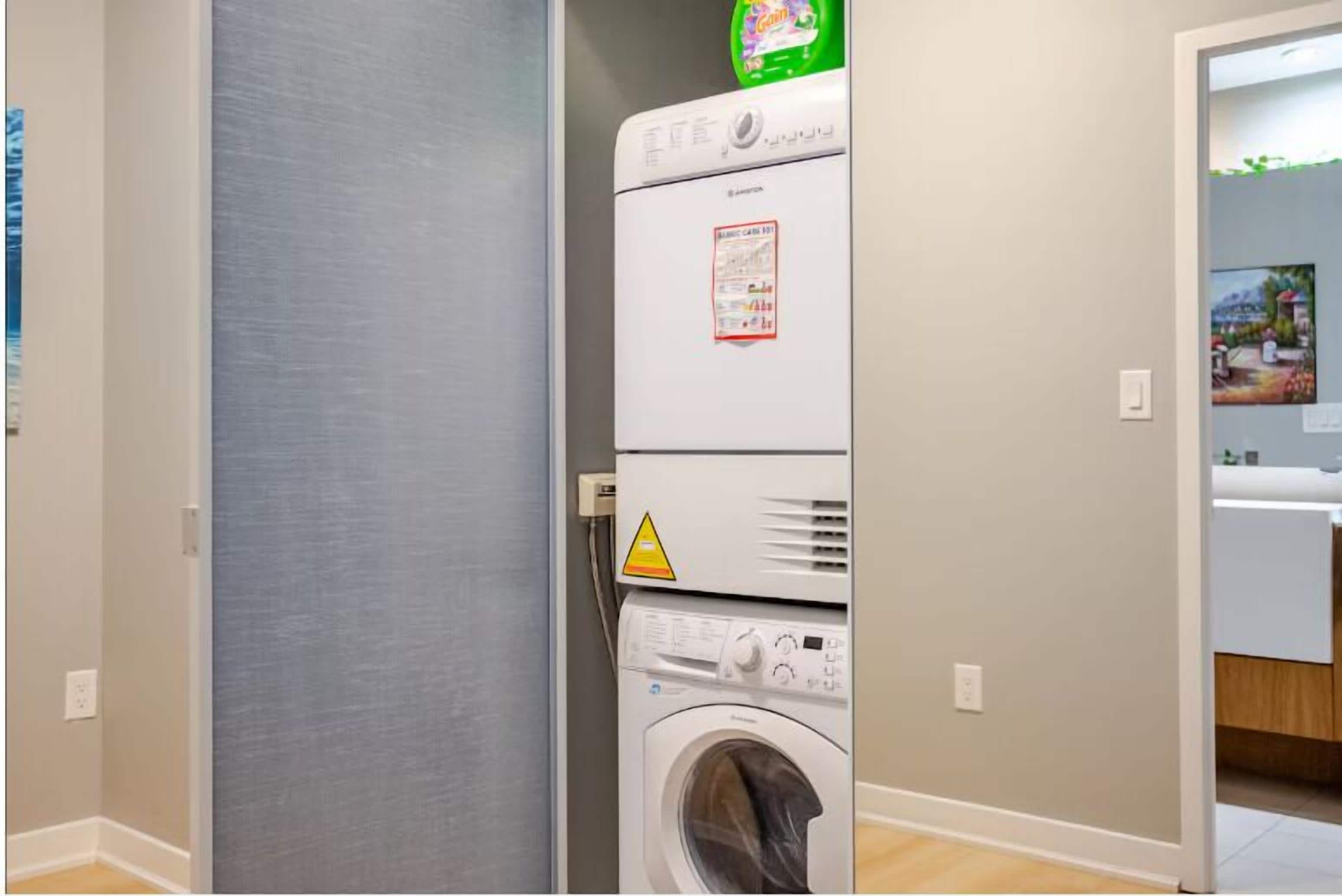 A laundry room with stacked appliances including a dryer and a washing machine.