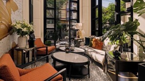 Een modern interieur met een bank, ronde tafels en grote ramen met uitzicht op de stad.
