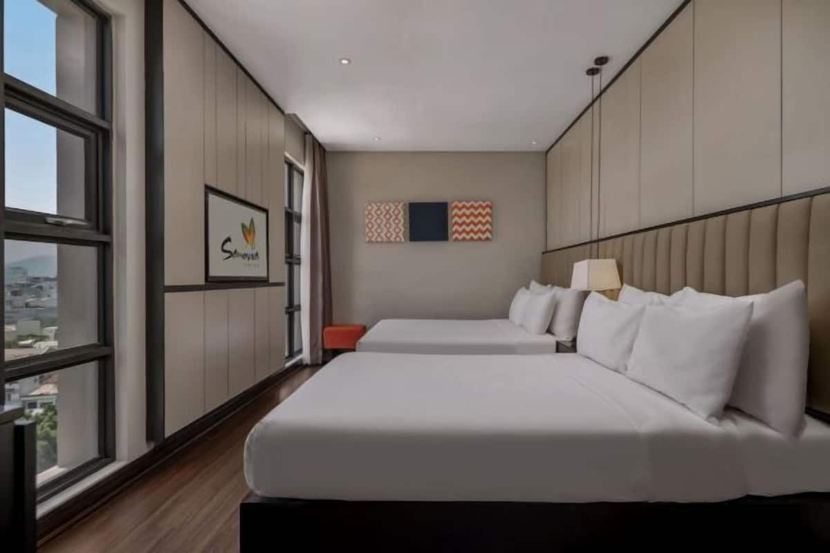 Ein Hotelzimmer mit zwei Betten, einem großen Fenster und Blick auf die Stadt.