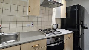Una cocina moderna con estufa a gas, horno, pileta de acero inoxidable y refrigerador negro.