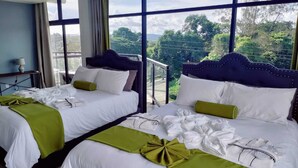A hotel room with two beds, large windows, and a view of greenery. - The Alexandria Marquis Hotel & Resorts (San Ignacio)
