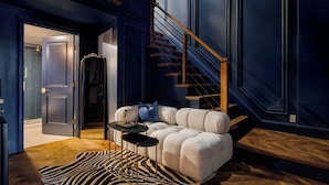 Uma sala de estar moderna com um sofá, uma mesa pequena, um tapete com padrão de zebra e uma escada.