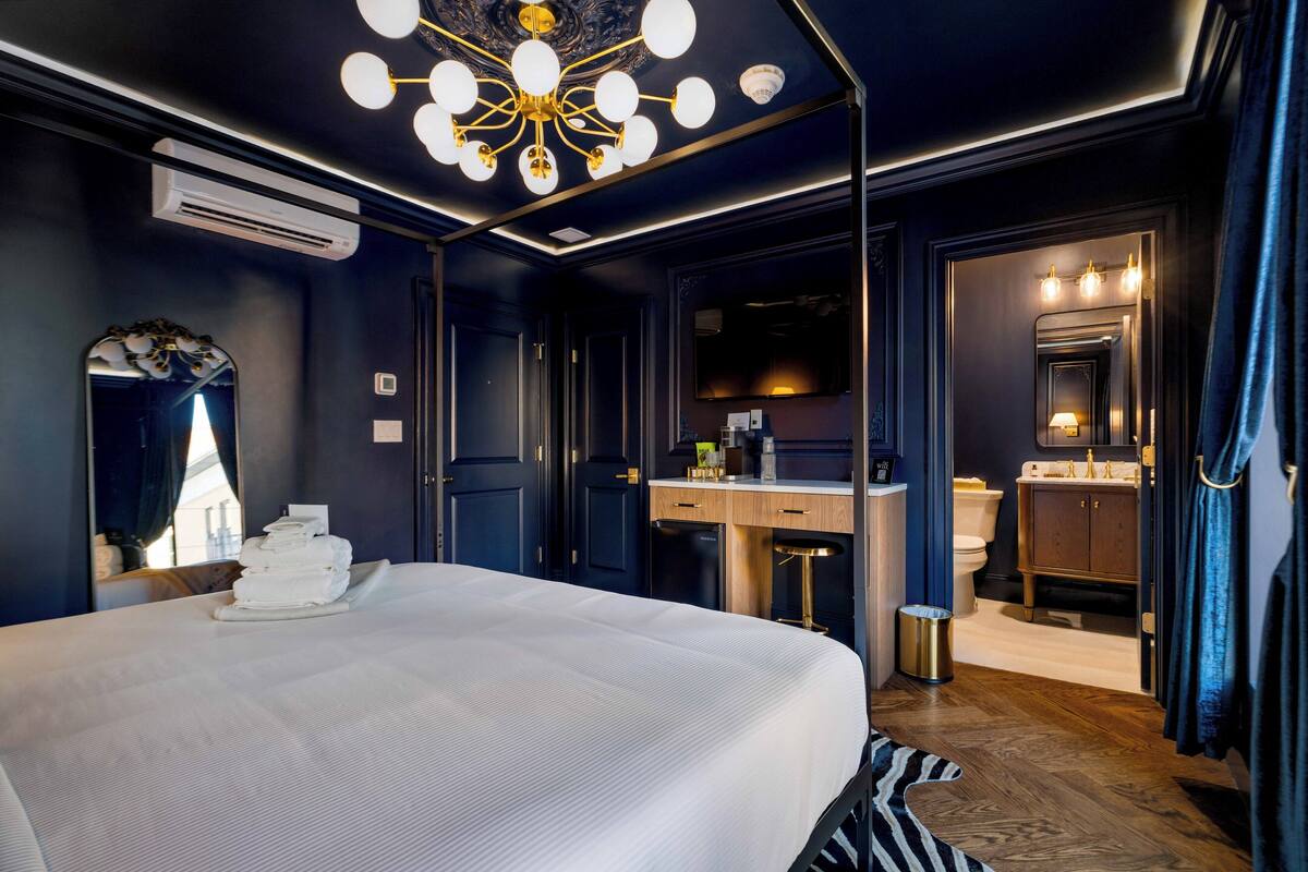 Ein modernes Hotelzimmer mit einem großen Bett, einem Schreibtisch, einem Schminktisch mit Spiegel und einer Kristallleuchter.