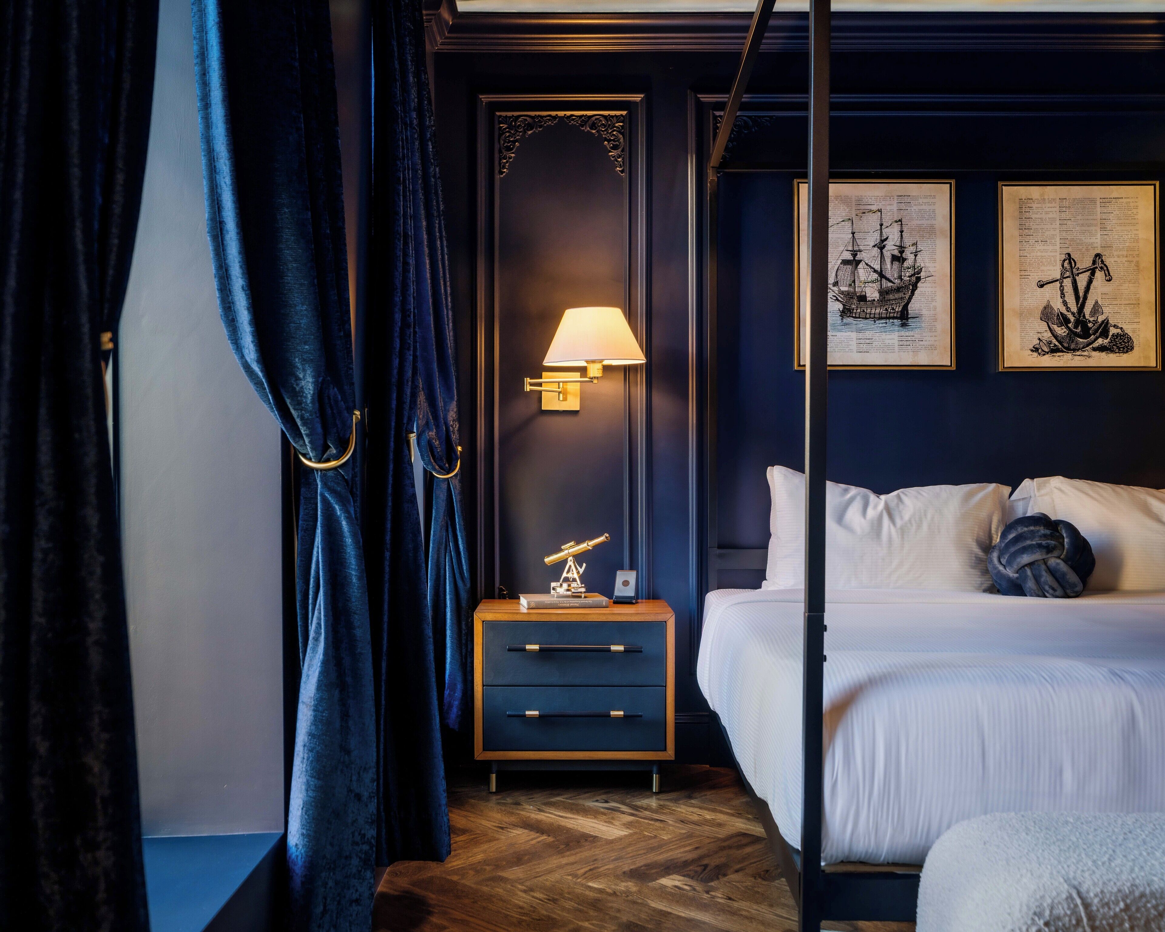 A bedroom with a bed, a nightstand with a lamp, and two framed pictures on the wall.