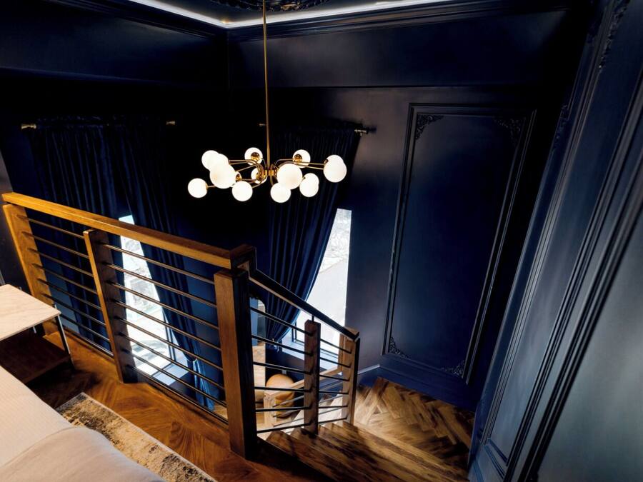 Un interior moderno con una escalera, una araña y vistas al exterior.