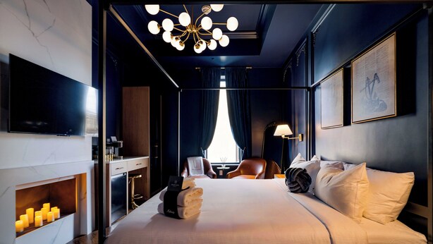 Quarto de hotel moderno com uma cama grande, televisão de tela plana, lareira e um lustre.