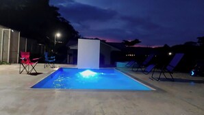 An outdoor swimming pool with a water feature at dusk. - Studio/Pool/WIFI-Full kitchen-A/C-Large Beach-Sunsets-Surf and Relax** (Provincia de Guanacaste)