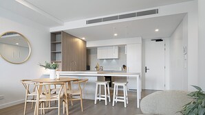 Una cocina moderna con armarios blancos, detalles de madera y una isla central con taburetes.