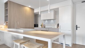 Cocina moderna con una isla central, muebles blancos y una pared de acento de madera.
