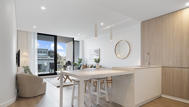 Una cocina moderna con una isla central, suelo de madera y un amplio ventanal con vistas a la ciudad.