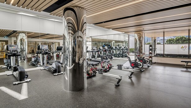 A modern gym with various exercise equipment, including treadmills, stationary bikes, and weight machines. - Chic 1-bed South Melbourne Unit With Pool & Gym (Melbourne)