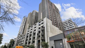 A high-rise building with multiple floors and balconies, surrounded by other buildings and trees. - Chic 1-bed South Melbourne Unit With Pool & Gym (Melbourne)