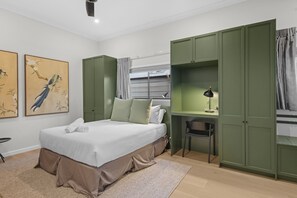 A bedroom with a bed, green wardrobe, desk, chair, and artwork. - Family-friendly 3-bed Apartment in New Farm (Brisbane)