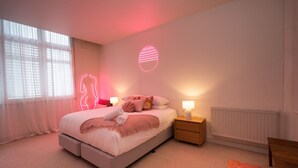 Ein modernes Schlafzimmer mit einem Bett, Nachttischen und einer Neonleuchte an der Wand.
