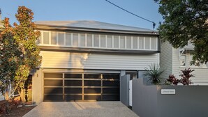 Een modern huis met twee verdiepingen, een garage, een naambord aan de muur en een verzorgde tuin.
