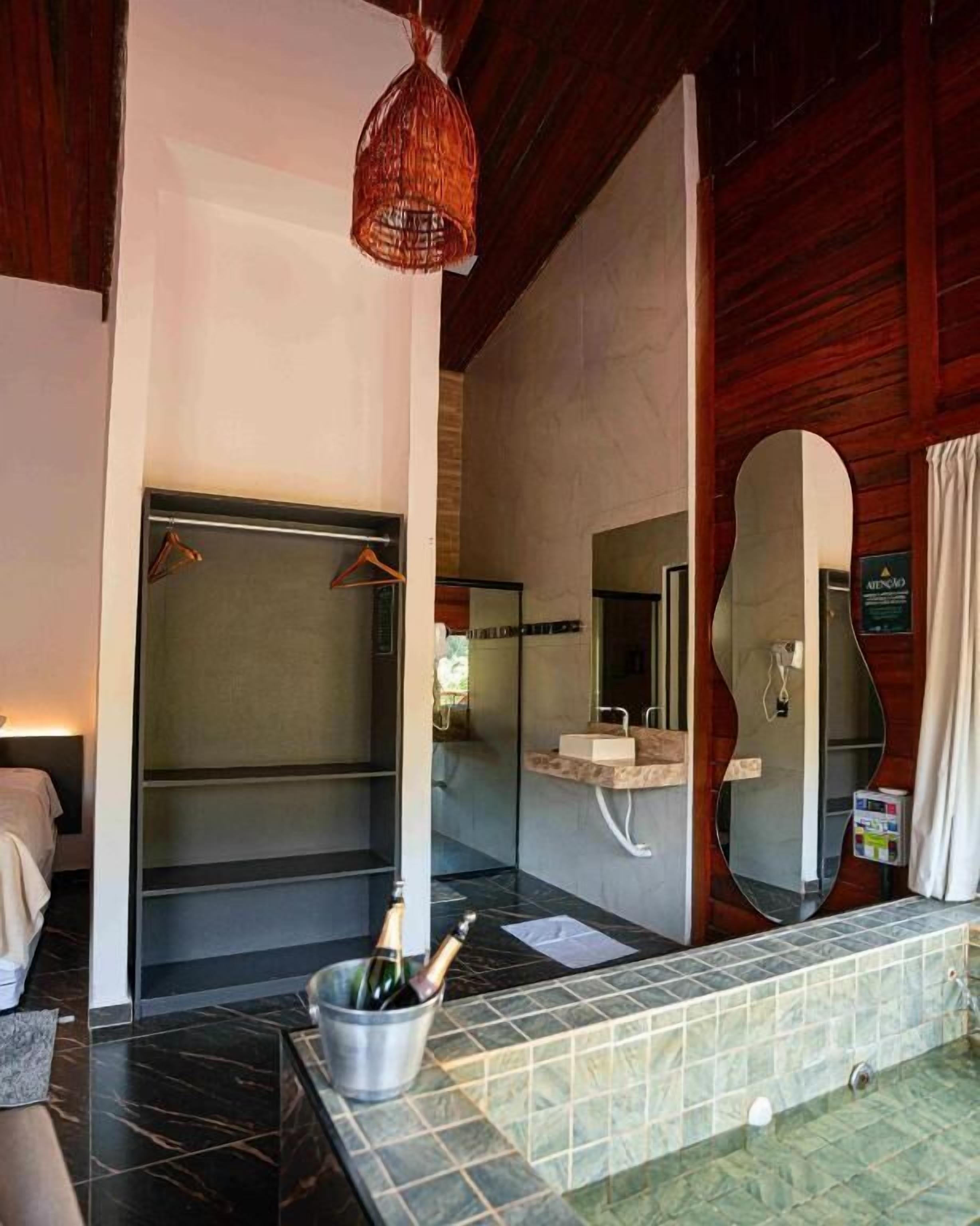 Un baño moderno con un espejo grande, una ducha y un lavabo. Hay un cubo con botellas en el suelo.
