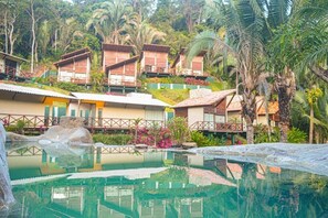 A resort with multiple bungalow-style accommodations, a central swimming pool, and lush tropical vegetation.