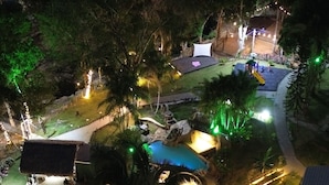 Eine Vogelperspektive zeigt ein Resort mit Schwimmbad, Sitzgelegenheiten im Freien und einer Bühne für Veranstaltungen.