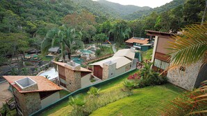 Ein Anwesen an einem Hang mit mehreren Gebäuden, einem Swimmingpool und üppiger Vegetation.