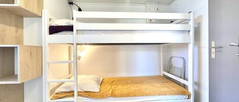 A bunk bed with a ladder, a shelf, and a door.