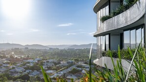 A modern building with a curved facade, large windows, and a rooftop garden. - City Escape With Balcony & Resort-style Amenities (Brisbane)