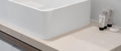A bathroom with a white sink and two skincare products on the counter.
