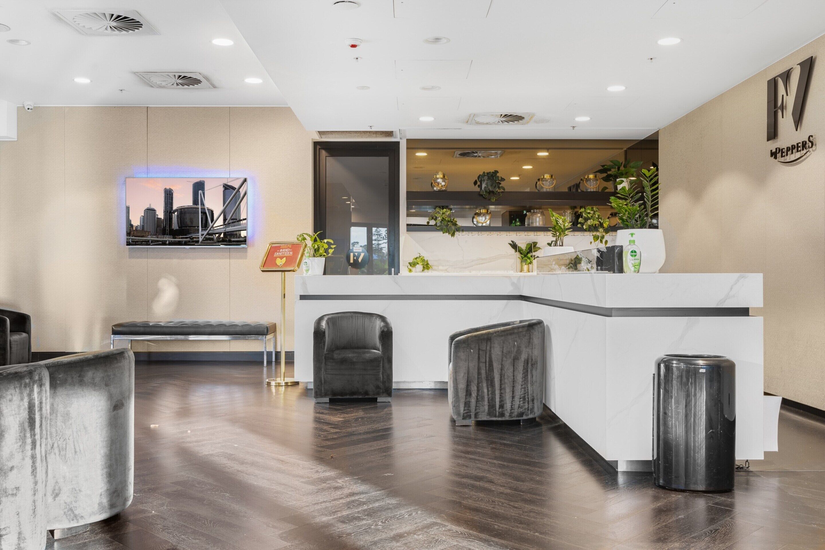 A reception area with a modern design, featuring a reception desk, seating area, and decorative plants.