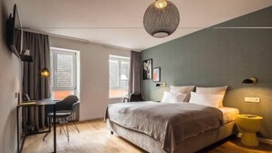 Une chambre à coucher comprenant un lit, un bureau, une chaise, un luminaire suspendu et une fenêtre.