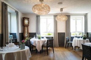 A dining area with round tables, chairs, and a large clock on the wall. - Genusshotel Krone & Roadtrips bei Basel (Inzlingen)