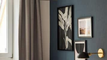 A room with a blue wall, a framed plant, and a framed picture.