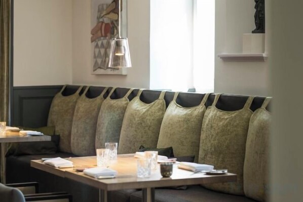 A restaurant seating area with a long bench, tables, and a hanging light fixture. - Genusshotel Krone & Roadtrips bei Basel (Inzlingen)