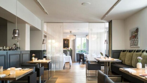 Un restaurant moderne avec des tables et des chaises en bois, un bar et une vue sur l’extérieur.
