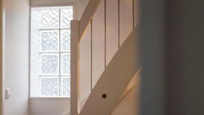 Un escalier avec une fenêtre en haut, qui mène à un palier.