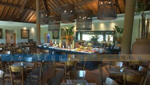 A restaurant with wooden tables and chairs, a buffet area with various food items, and hanging wicker lamps. - Luxury Pool View at La Fleur Polynesia (Porto de Galinhas)