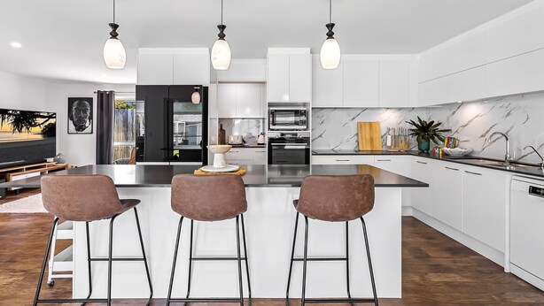 A modern kitchen with white cabinets, a marble backsplash, and three bar stools. - Family-friendly Home With Private Pool and BBQ (Sunshine Coast)