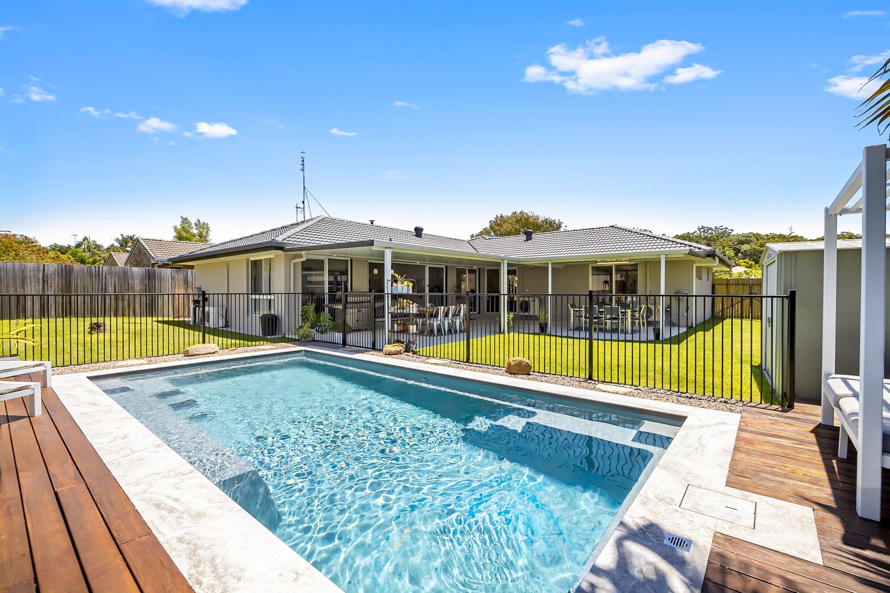Una propiedad residencial con piscina, terraza cubierta y patio cercado.