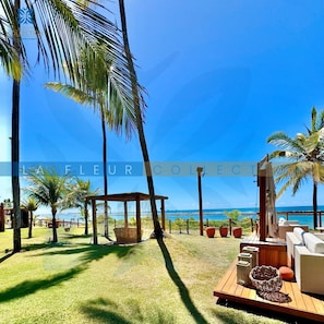 A beachside lounge with a wooden deck, seating, and a view of the ocean.