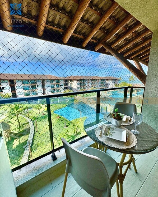 Un balcón con vista a una piscina y el edificio de un hotel.